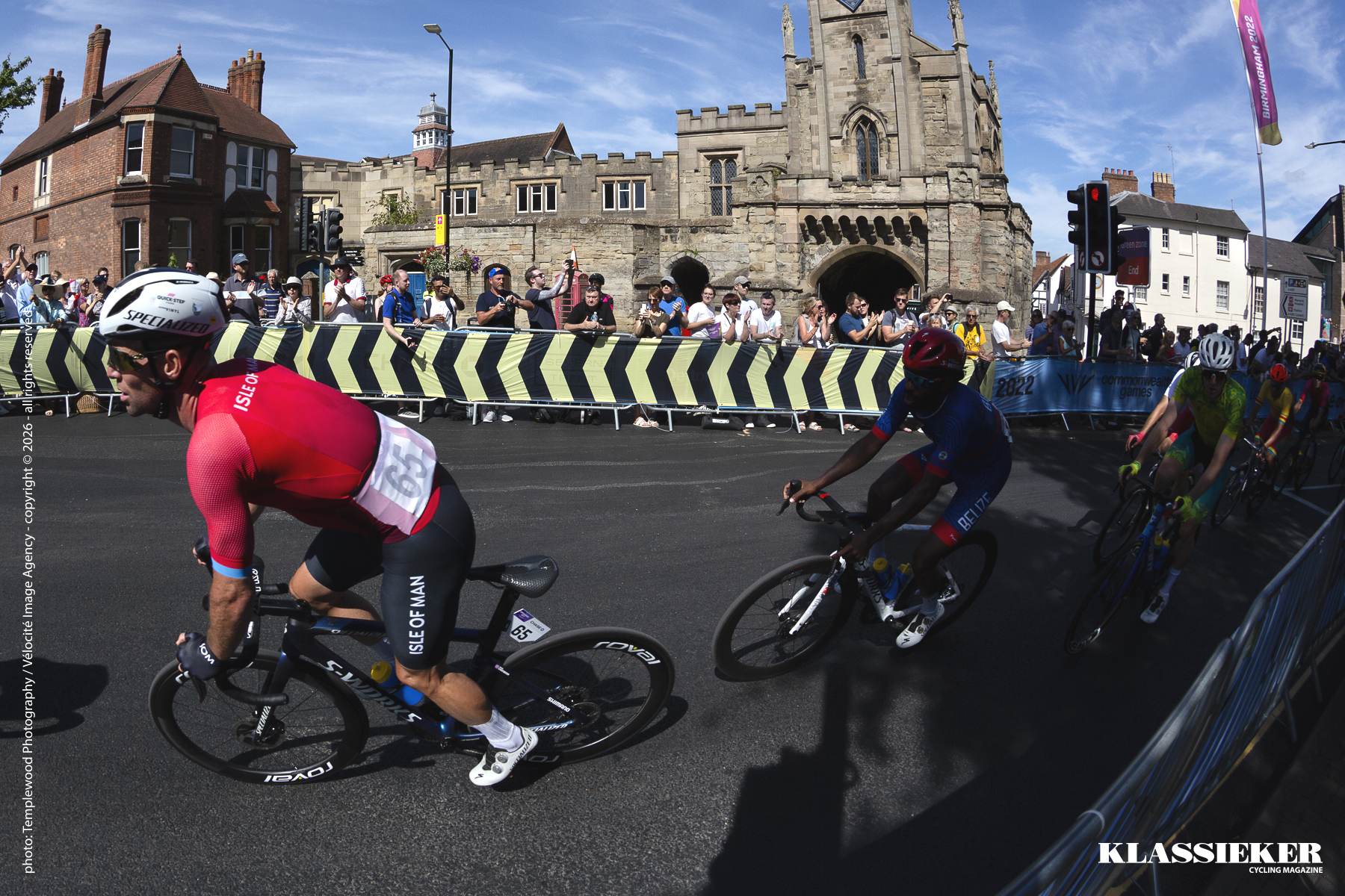 Mark Cavendish rounds a corner in front of an impressive building as he competes in the road race on the streets of Warwick at the 2022 Commonwealth Games