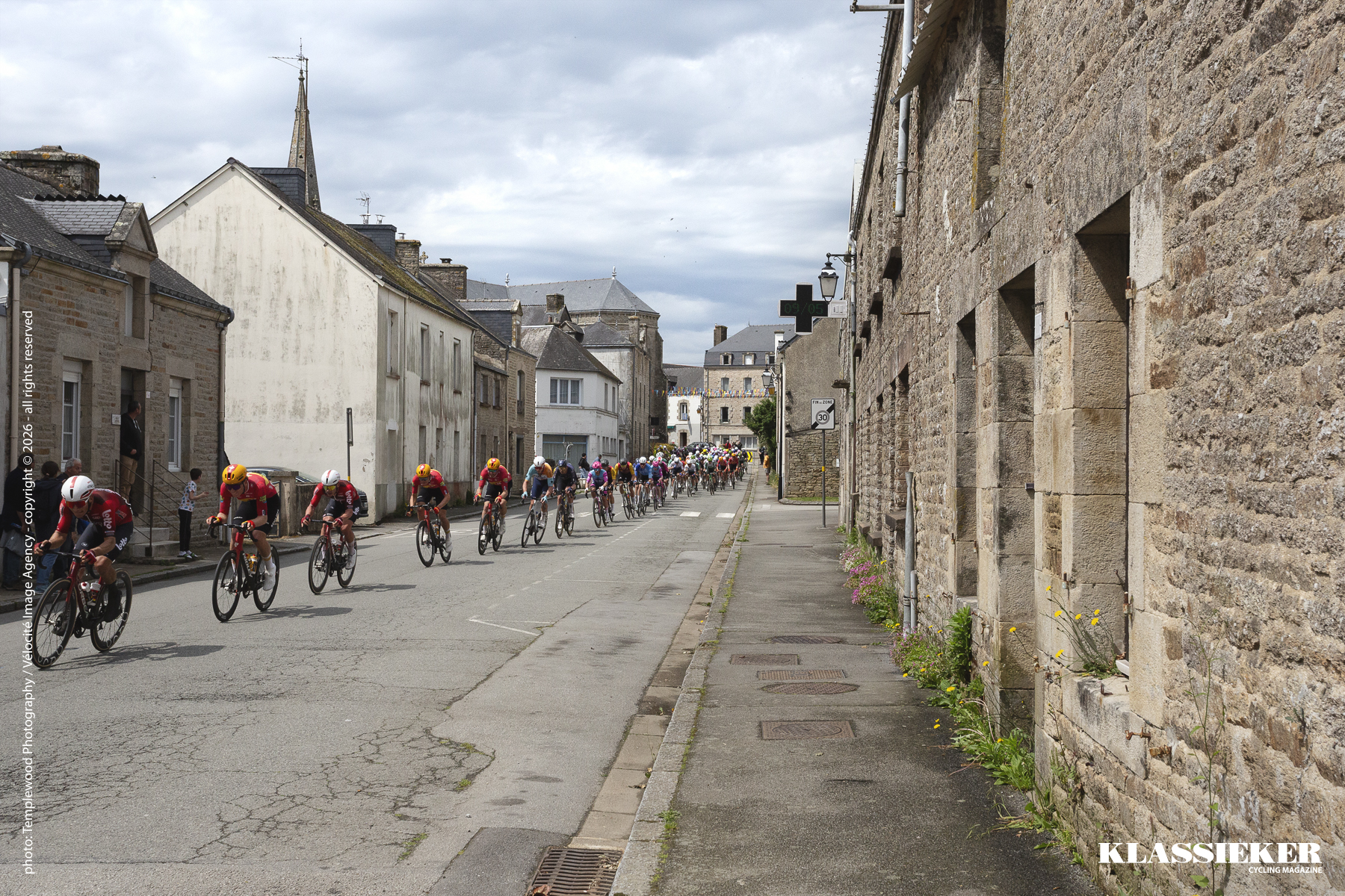 Riders race through the streets of Plumelec past stone houses