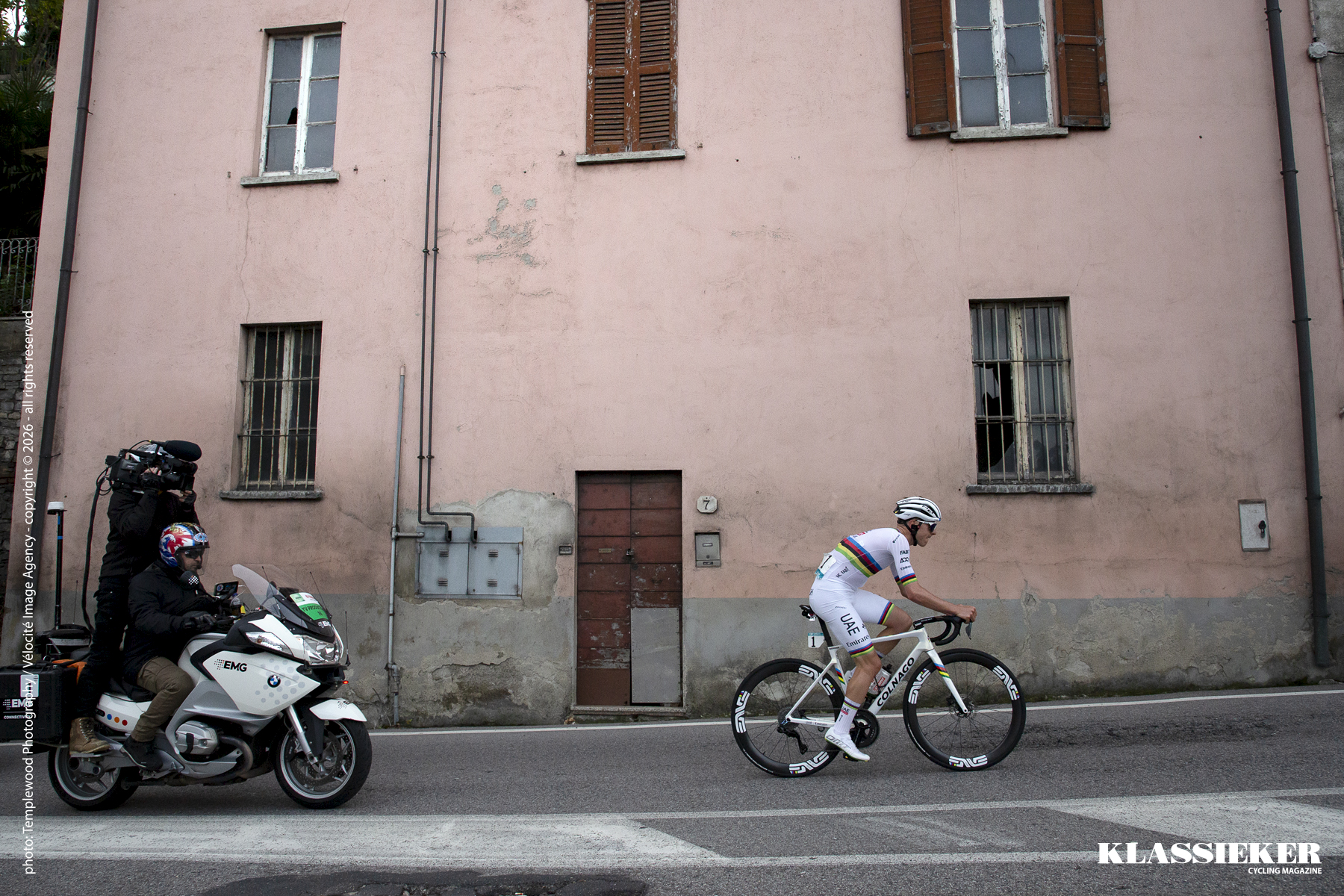 Il Lombardia 2024 - Tadej Pogačar rides past a pastel pink building in Como