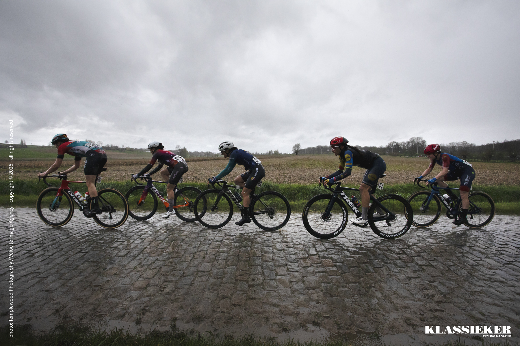 Ronde Van Vlaanderen 2024 - Riders in wet conditions seen from the side on the cobbles of Mariaborrestraat
