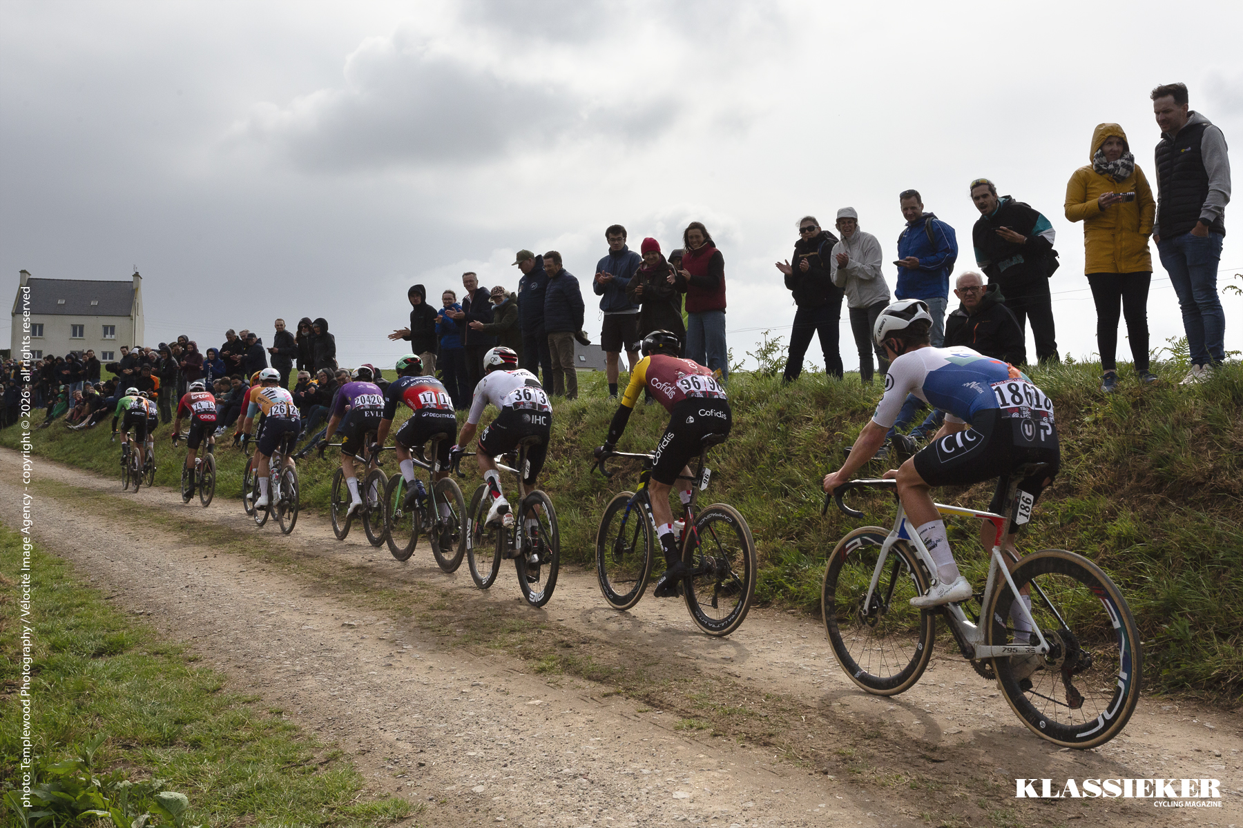 Fans line the high road side banks as riders pass on the farm track beneath them during Tro Bro Leon 2026