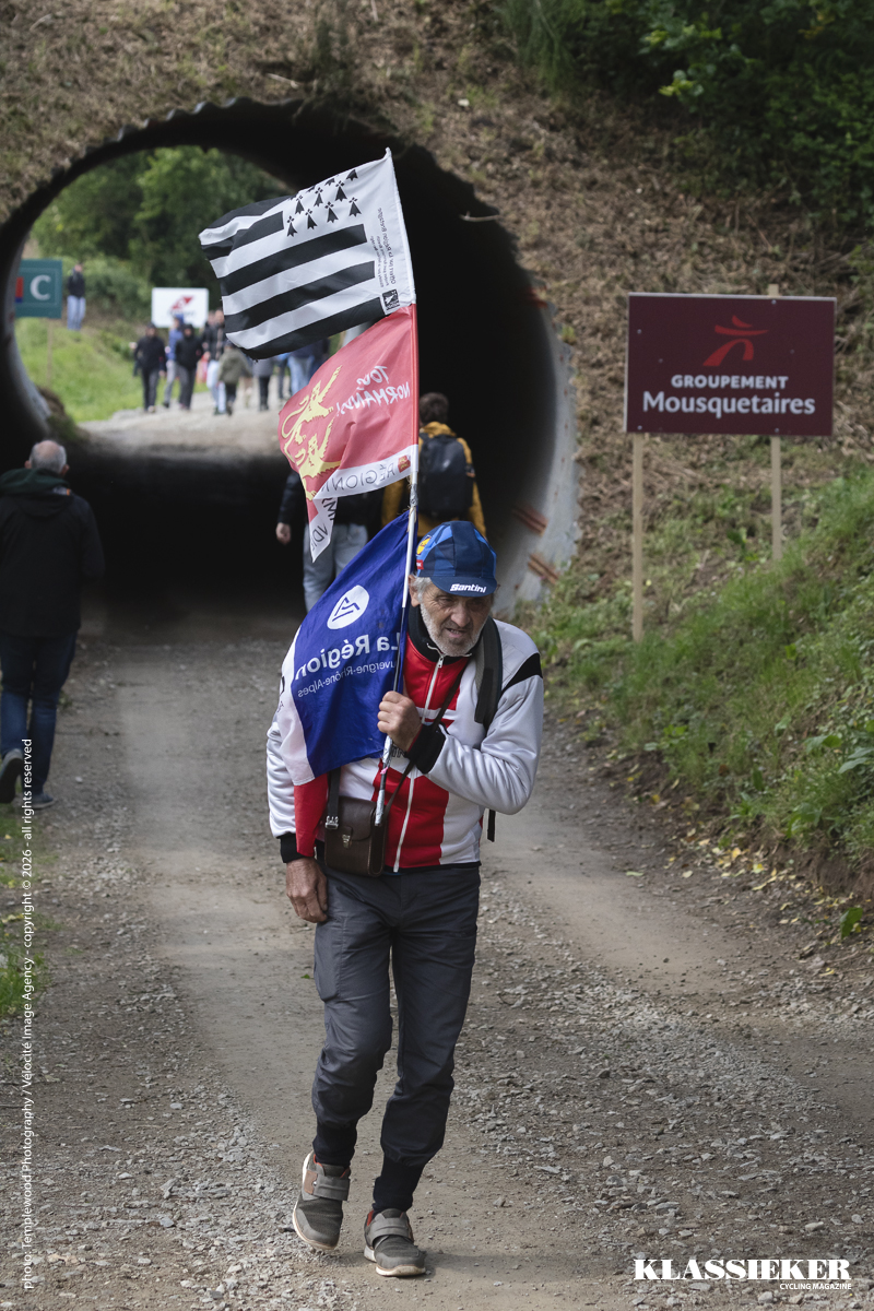 Tro Bro Leon 2026 - A veteran fan carries a flag pole with a number of flags hung from it