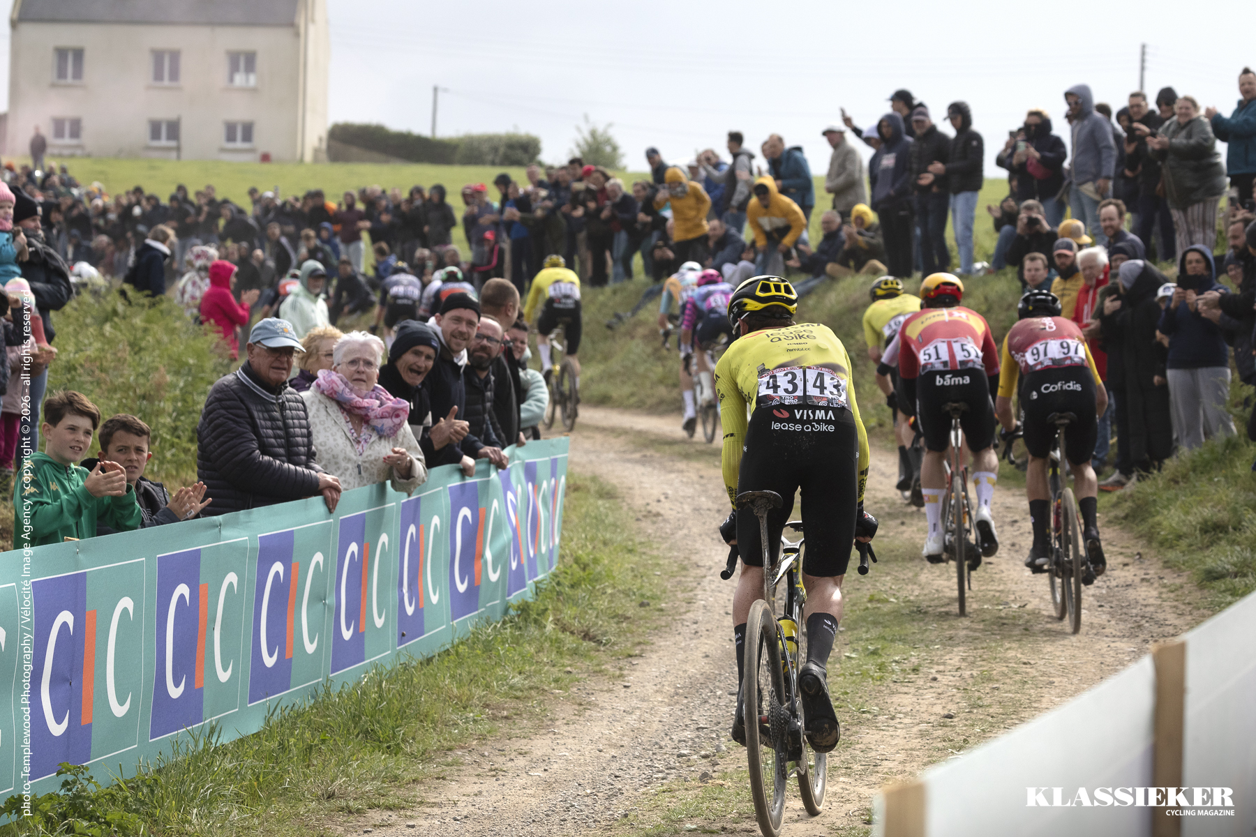 Tro Bro Leon 2026 - Filippo Fiorelli of Team Visma - Lease a Bike seen from the rear mid climb on an unpaved surface with fans lining the side of the course
