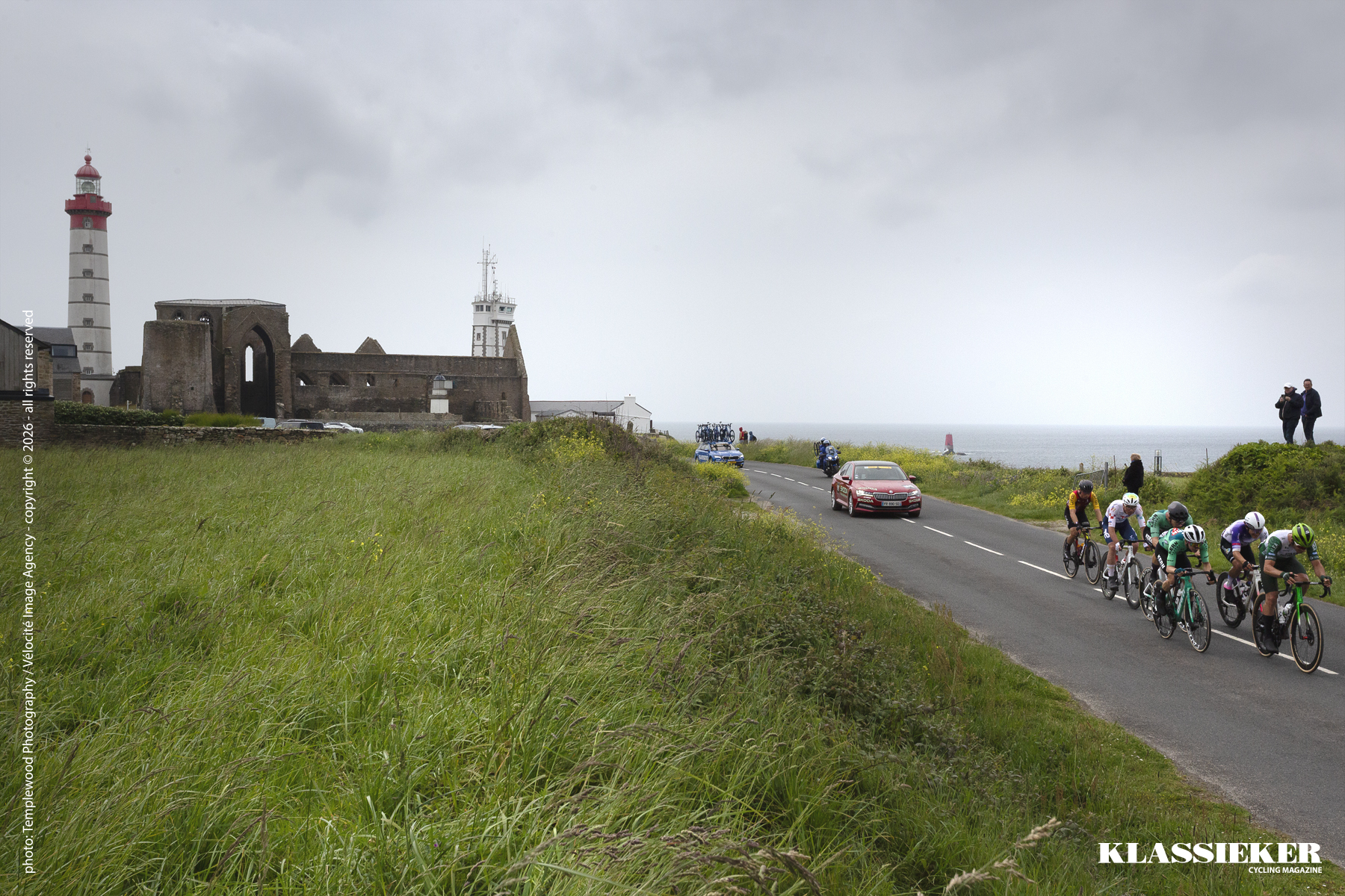 Tro Bro Leon 2026 - Riders on the coastal road at Pointe Saint-Mathieu with a lighthouse and abbey in the background